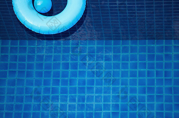 游泳圈和玩具球漂浮在蓝色的游泳池里