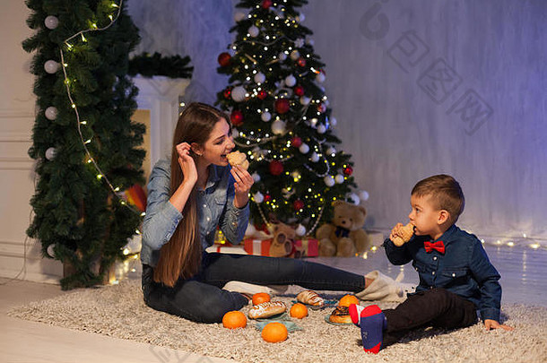 母亲和儿子在圣诞树上吃橘子
