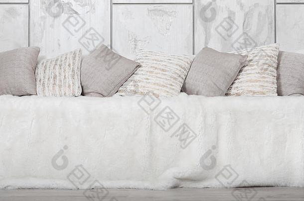 沙发上躺着许多枕头，在大理石墙的背景下，沙发上覆盖着一层巨大的毛绒面纱