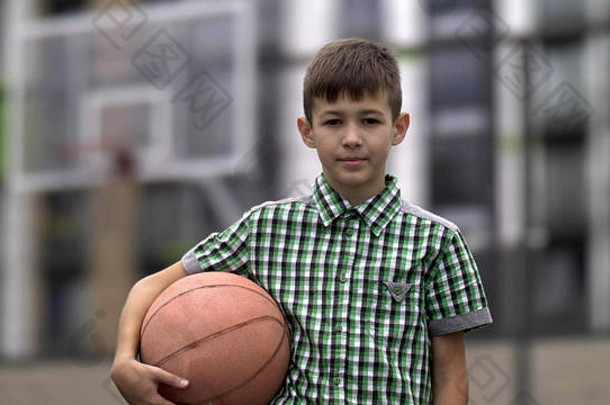 篮球场上一个男孩拿着篮球的肖像，看着相机