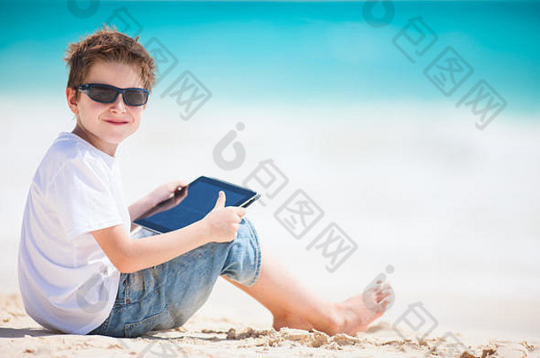 海滩上玩平板电脑的小男孩