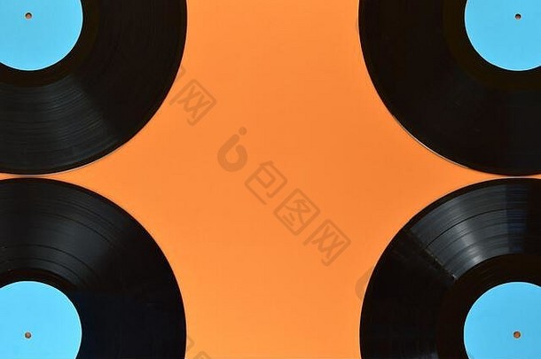 四个旧的黑色乙烯基记录，在橙色背景和中间空间上有空白青色标签。