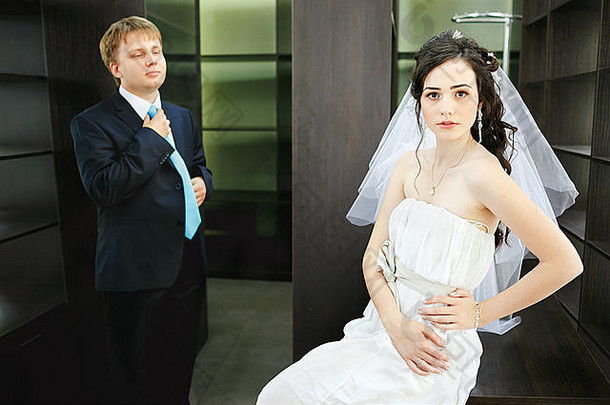 以新婚夫妇为背景的办公室家具空柜，<strong>男女关系</strong>。美丽的新娘戴着朴素的白色婚纱，新郎套装配上绿松石领带。婚纱照。