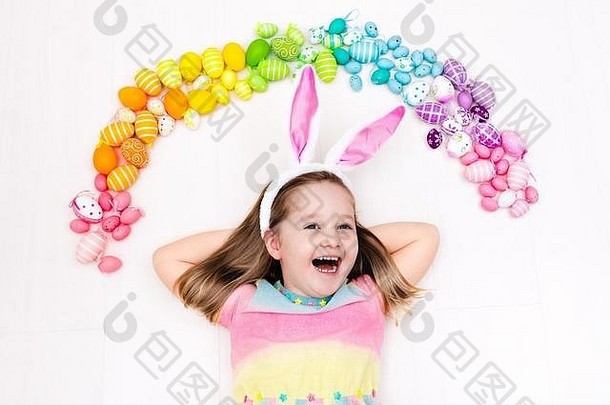 有<strong>兔</strong>子耳朵的有趣小女孩在寻找复活节彩蛋时玩得很开心。玩彩色复活节彩蛋的孩子。孩子们玩彩色彩虹蛋。服务提供商