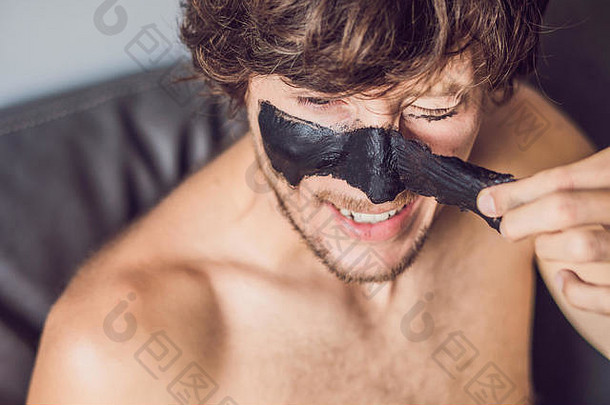 脸上戴着黑色面具的快乐男人。照片中的男人正在接受水疗。美容护肤理念