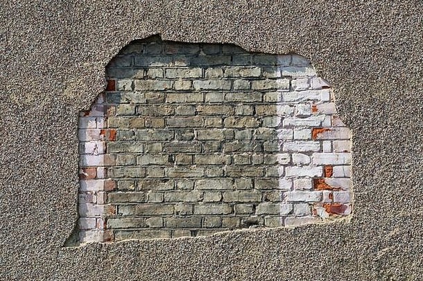 从<strong>房屋</strong>外部脱落的大面积抹灰，露出下面的砖墙。