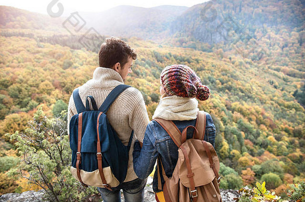 美丽的夫妇背着背包在多彩的秋林中