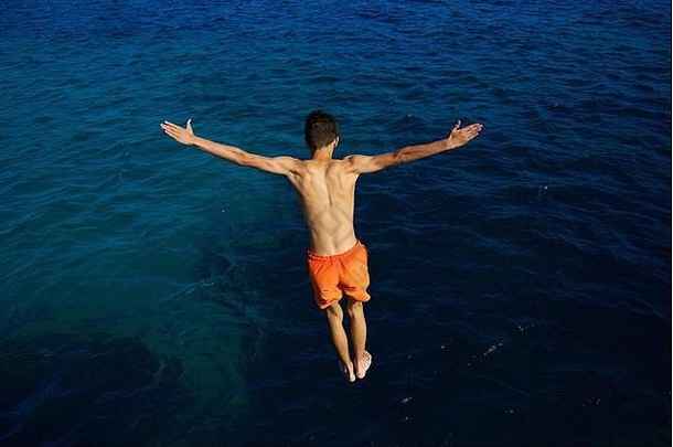 十几岁的男孩跳蓝色的海夏天假期有趣的马略卡岛西班牙