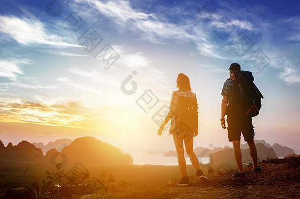 徒步旅行者背着背包在山顶上观赏日出