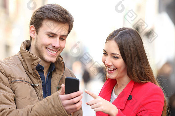 快乐夫妇在冬天在街上查看智能手机内容