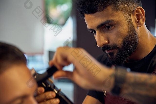 主人在理发店为男人理发，理发师为一个年轻人做发型。在理发店工作，理发的过程