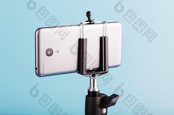 智能手机在一个三脚架上，作为一个蓝色背景的博客的摄影摄像机。录制视频和照片。