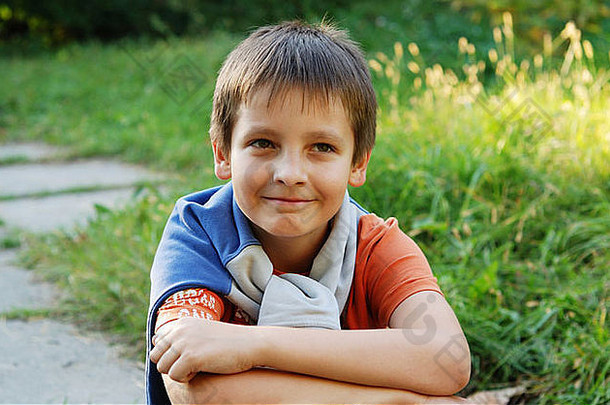 十二岁的漂亮男孩坐在小路上