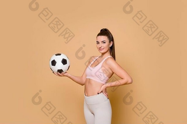年轻漂亮的运动女郎，手里拿着足球。以骆驼为背景隔离