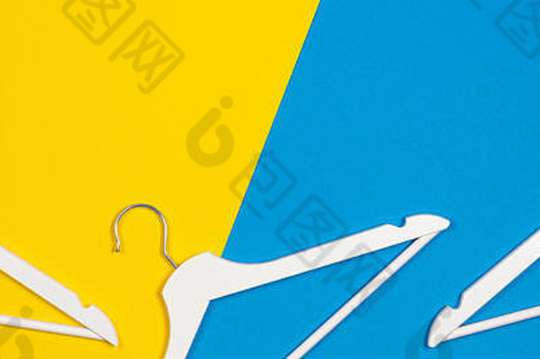 两个白色木制衣架，背景为黄色和浅蓝色。购物、销售、促销、社交媒体、新赛季概念
