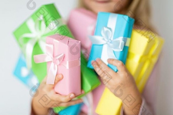 节礼日收到礼物的快乐孩子。小女孩微笑着拿着包装好的礼物盒。戴粉红色帽子的小孩，手里拿着生日礼物