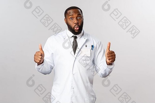 印象深刻的英俊的非洲裔美国大胡子男医生的肖像推荐伟大的诊所，医院服务，竖起大拇指，说哇和凝视