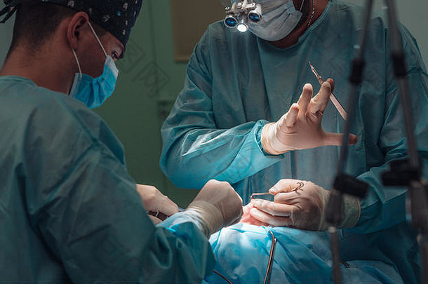 外科医生和他的助手在鼻子上做整容手术