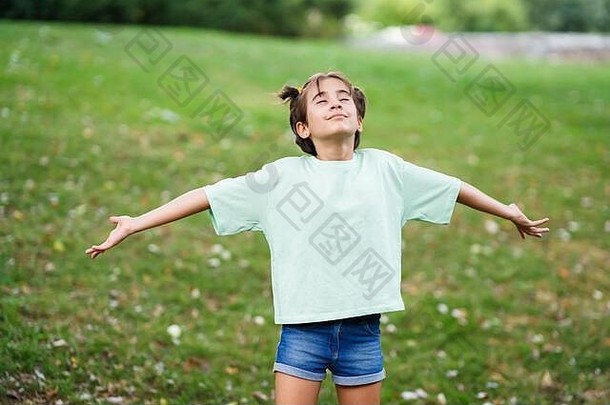 九岁女孩张开双臂在草地上呼吸