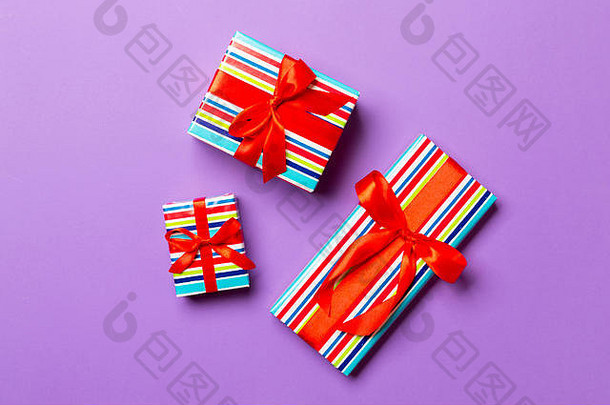 用紫色<strong>背景</strong>上的红丝带用纸包好的圣诞节或其他节日手工礼品。礼品盒，彩<strong>台</strong>礼品装饰，t
