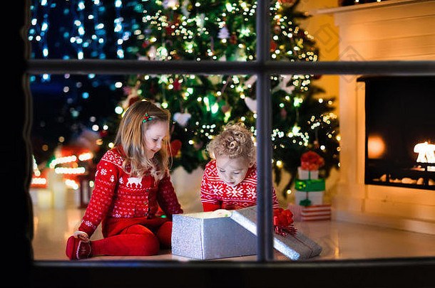 快乐孩子们匹配红色的针织毛衣装修圣诞节树美丽的生活房间传统的火的地方