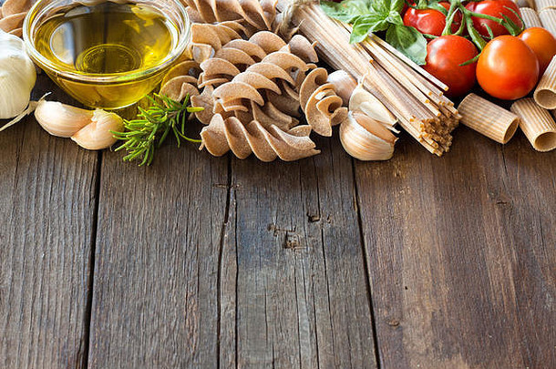 橄榄油、意大利面、大蒜和西红柿放在木桌上