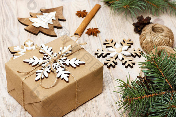 以<strong>牛皮纸包装</strong>的礼品盒、冷杉树枝、松果、肉桂枝和八角星为圣诞背景，白色木质背景