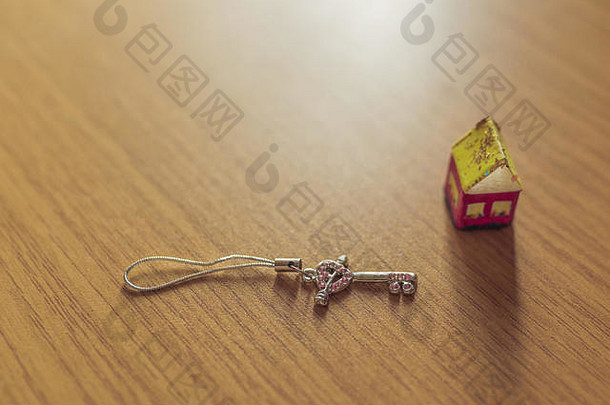 一个由纸和钥匙组成的小玩具屋放在一张木桌上