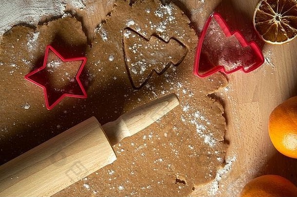 木制桌子上的圣诞姜饼和饼干切割器的面团