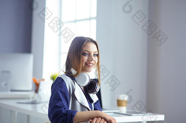 戴着耳机的专注专注的女人坐在桌旁，拿着笔记本电脑，看着屏幕，做笔记，在互联网上学习<strong>外语</strong>