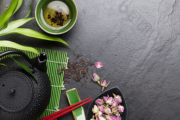 亚洲寿司筷子，玫瑰茶和茶壶在石桌上。具有空间的俯视图