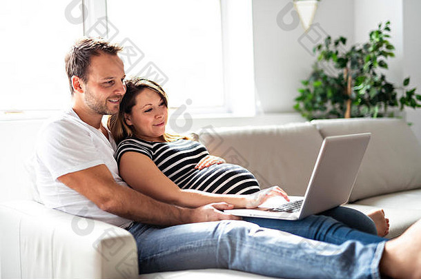 一对夫妇和孕妇一起使用笔记本电脑