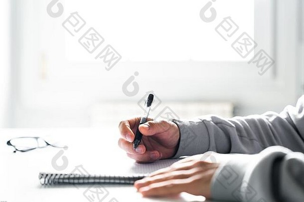 学生在家里的书桌上写作业，在笔记本上写字