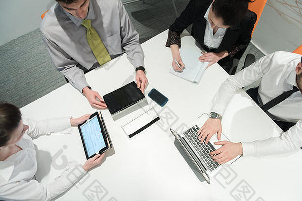 商务人士小组在会议上集思广益的鸟瞰图，以及商人在笔记本电脑和t