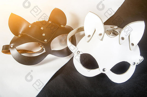 特写两个手工制作的猫面具，黑色和白色的野兔从真正的皮革化装舞会，在黑色和白色的桌子上<strong>新年</strong>