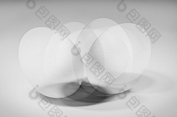 一个白色鸡蛋在白色背景下旋转的多重曝光照片