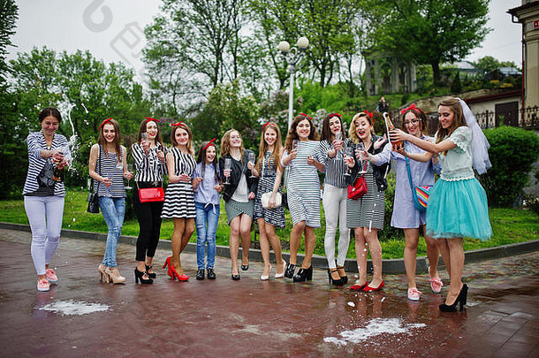 十一位漂亮的辫子女郎和可爱的新娘在公园里用香槟庆祝单身派对。