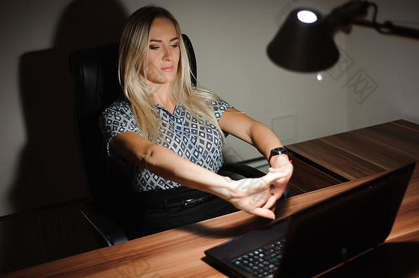 一位压力很大的女商人坐在办公桌前，在电脑前工作到很晚时思考解决方案。