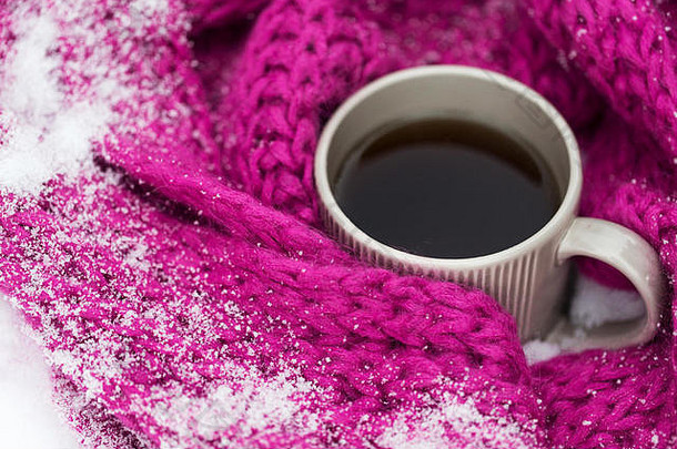 茶或咖啡的特写镜头和雪中的冬季围巾