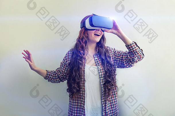 在白色背景下，戴着虚拟现实VR眼镜和头盔耳机的年轻女子微笑。智能手机使用虚拟现实护目镜。技术、模拟、高<strong>科技</strong>、电子游戏概念