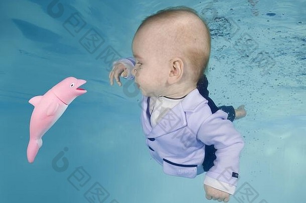 一个男孩打扮成小老板，在游泳池里潜入水中