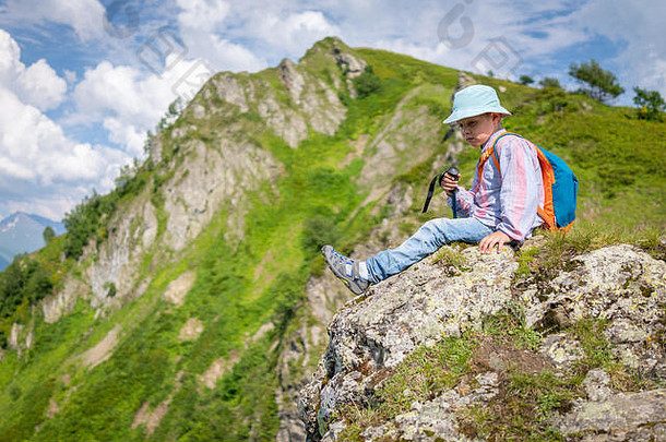 一个在巴拿马旅行的男孩拿着<strong>登山杖</strong>和背包在山顶上休息。高加索，俄罗斯