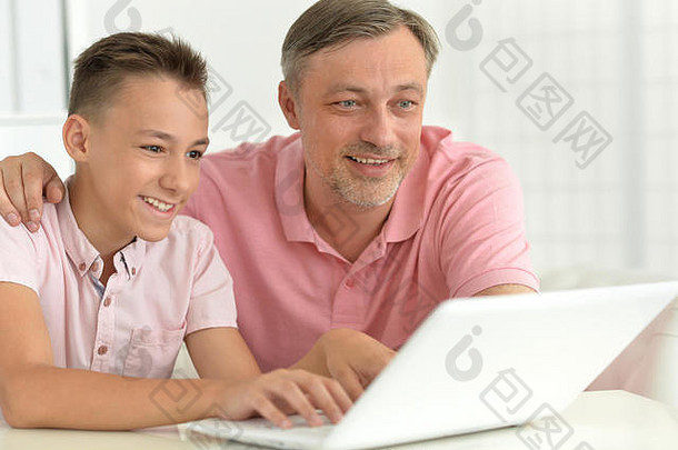 儿子和父亲在家使用笔记本电脑