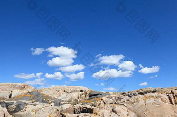 度假胜地里瑟郊外的一个小岛上，白色的棉花云和色彩斑斓但光滑的岩石斜坡点缀着蔚蓝的天空
