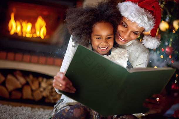 圣诞节晚上，可爱的小女孩和妈妈一起读童话故事