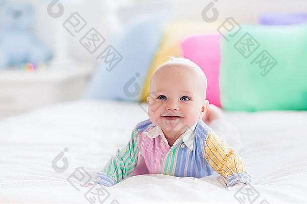 白色卧室里的。婴儿躺在床上，有彩色软垫。儿童托儿所。纺织品、枕头和床上用品