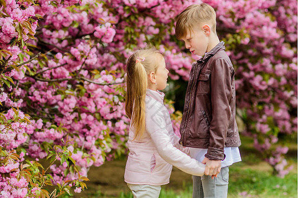 <strong>春</strong>天是坠入爱河的时候。恋爱中的孩子粉色樱花。爱在空气中。一对可爱的孩子漫步樱花花园。温柔的爱情。小女孩和男孩。在公园里的浪漫<strong>约会</strong>。