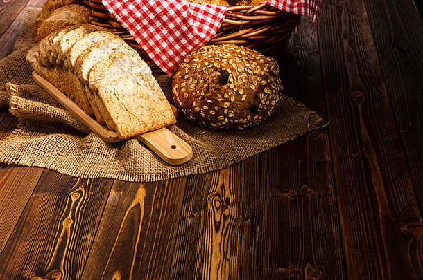 深色背景木质桌子上的面包店产品组合。自然晨光下各种面包的静物画。。