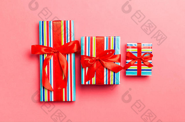 用红丝带在活珊瑚背景上的纸包装圣诞或其他节日手工礼品。礼品盒，彩色ta上的礼品装饰