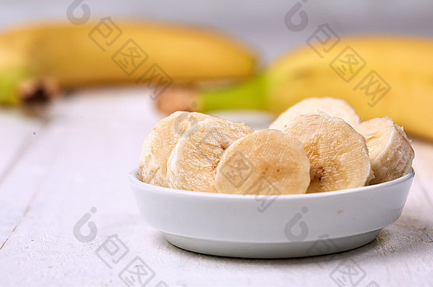 切片香蕉白色碗白色表格前面香蕉黄色的皮